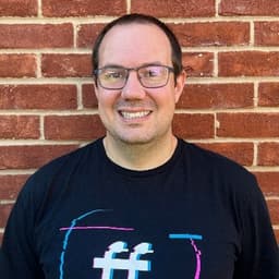 Photo of Jonathan Fielding stood against a wall wearing a FFconf tshirt